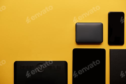 Preview: top view of graphics tablet with digital tablet, smartphone and portable hdd on yellow surface