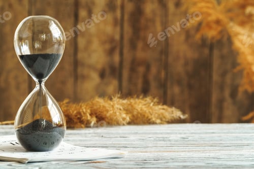 Preview: Hourglass with calendar on wooden desk close up