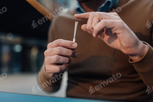 Preview: Man holding a hand-rolled cigarette, preparing to smoke