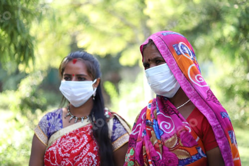 Preview: Closeup shot of two Indian women with traditional dresses and white masks