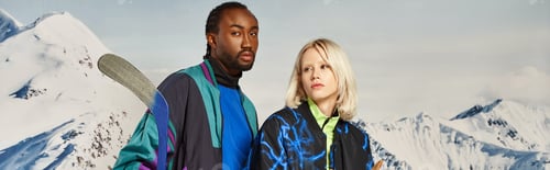Preview: beautiful interracial couple posing with hockey stick with mountain backdrop, winter concept, banner