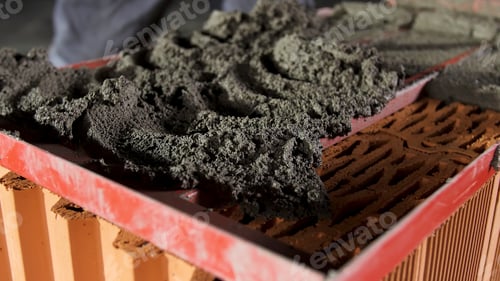 Preview: Bricklayer putting down raw cement and making an even layer to put another brick on it. Stock