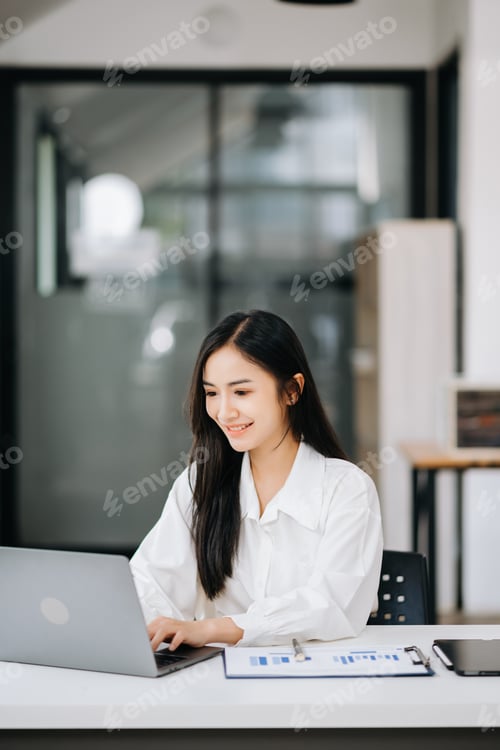 Preview: Beautiful Asian business woman typing laptop and tablet Placed at the table at office