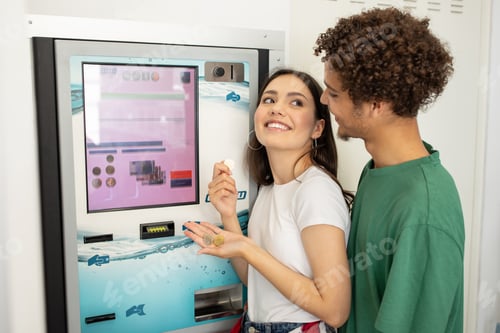 Preview: Young couple enjoying snacks from a vending machine in a bright hallway