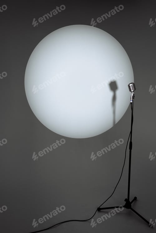 Preview: Microphone against illuminated circular light, artistic shadow.