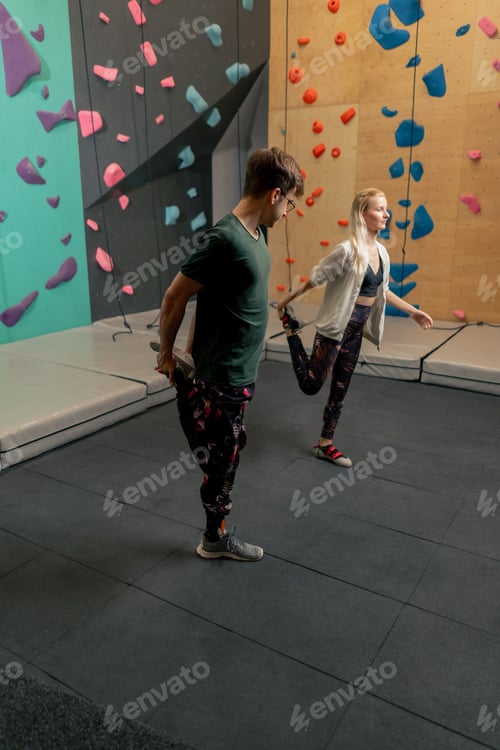 Preview: young girl at a climbing wall with a trainer doing a warm-up before rock climbing training