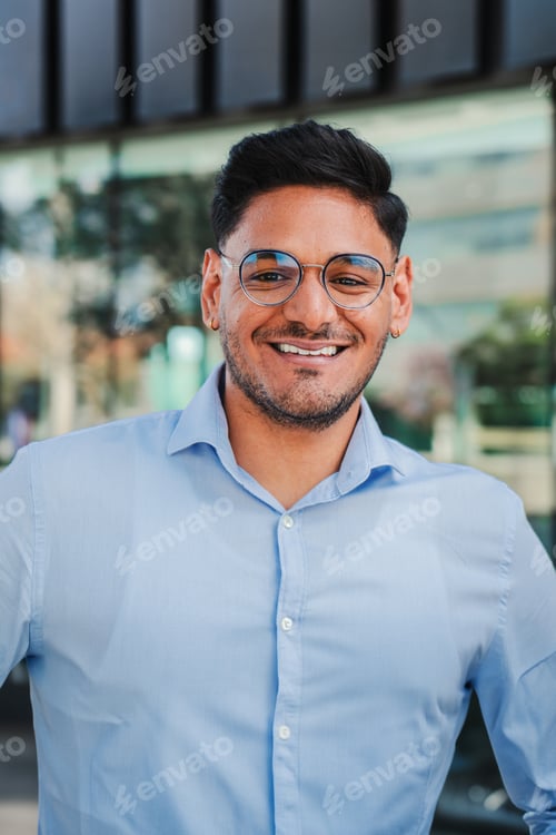 Preview: Vertical portrait of hispanic young entrepreneur smiling and looking at camera at workspace. Front