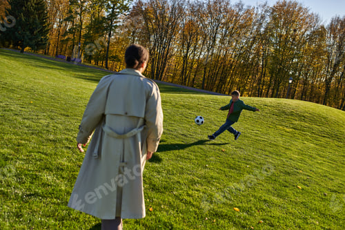 Preview: cute african american boy playing football near mother on green field, soccer, autumn, fall season