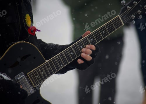 Preview: Guitarist playing guitar in the snow outside on a cold December day