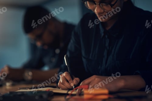 Preview: Shot of a young technician writing in a notebook while repairing computer hardware