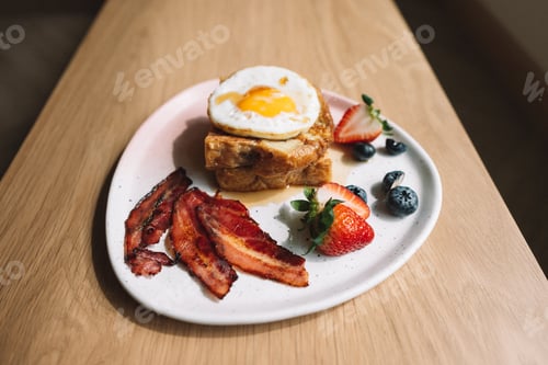 Preview: French toast with egg bacon strawberry and blueberry on wooden table, top view