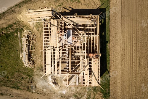 Preview: Aerial view of unfinished brick house with wooden roof frame structure under construction.