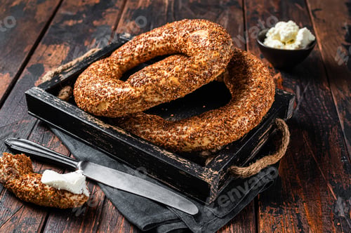 Preview: Stack of fresh baked Turkish simit bagel with kaymak. Wooden background. Top view