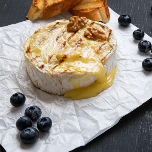 Preview: Grilled camembert cheese in paper with toasts, blueberries and walnuts.