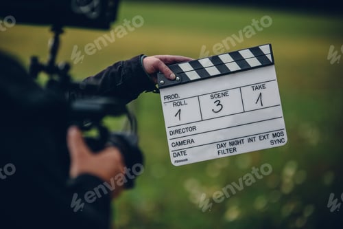 Preview: Shallow focus shot of the cameraman holding a clapperboard in the field