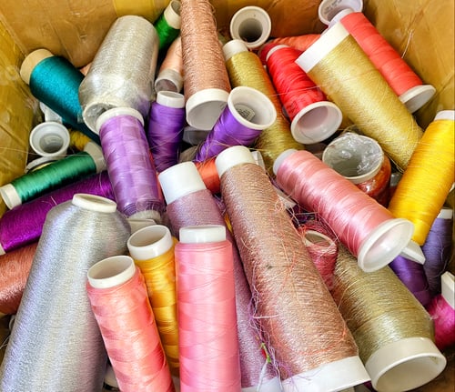 Preview: Colorful random spools of fine silk brightly colored thread in random bundle in a local tailor shop