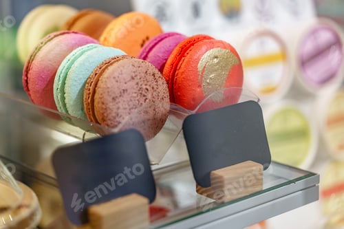 Preview: Colorful macarons displayed in a dessert shop case during a sunny afternoon