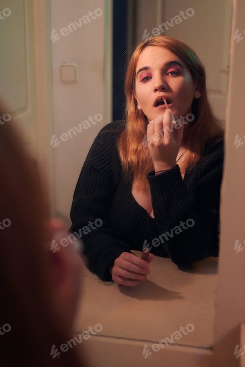 Preview: Young woman paints her lips in front of her bedroom mirror
