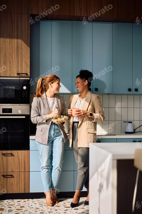 Preview: Cheerful businesswomen communicating on a break in shared office kitchen.