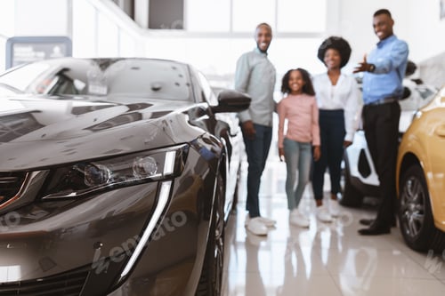 Preview: Happy young salesman helping African American family choose luxury car at vehicle dealership