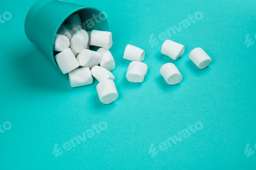 marshmallow laid out on blue paper background. pastel creative textured pattern