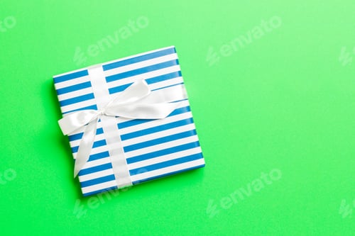 Preview: wrapped Christmas or other holiday handmade present in paper with white ribbon