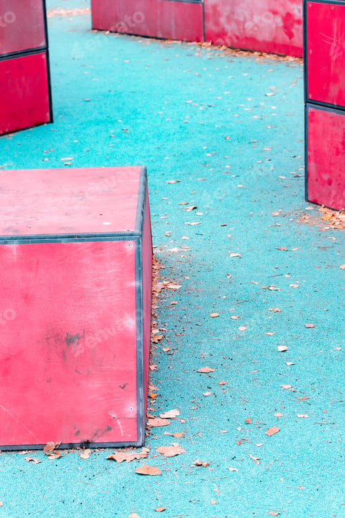 Preview: Blue rubber playground with red bars and fallen leaves: Active outdoor fun among triangular shapes.