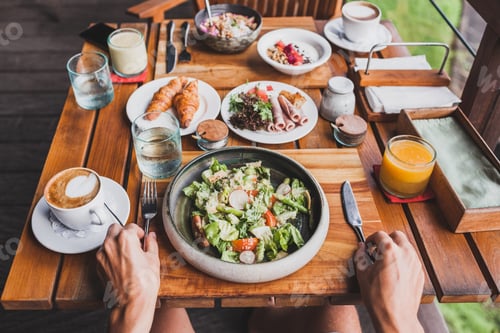 Preview: View from above on table with fresh breakfast. Man hands holding fork and knife
