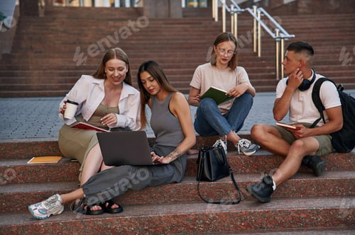 Preview: Relaxed, on the stairs, with laptop. Group of students are outside together