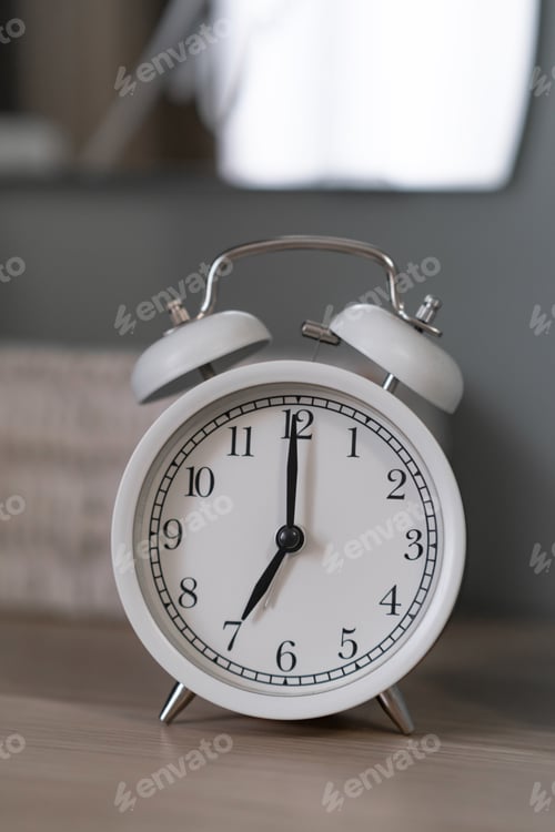Preview: Close-up of a round white alarm clock on a table in the bedroom.