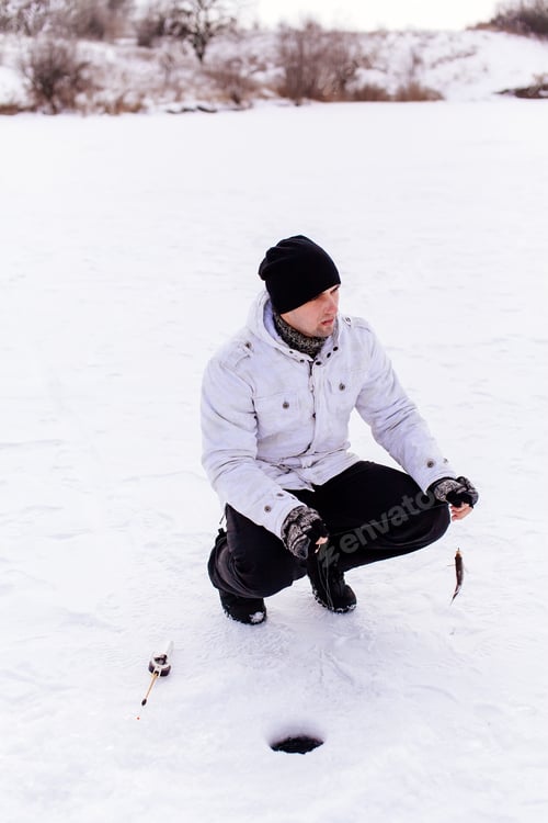 Preview: winter fisherman with jig and fish on frozen lake