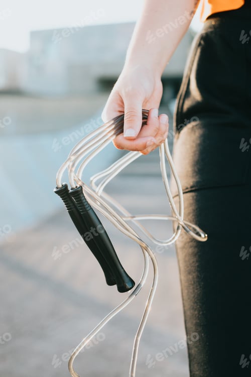 Preview: Close up of young hand holding a jump rope training outside. Preparing herself for coaching. Cardio
