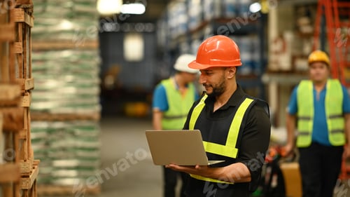 Preview: Storehouse employees workers in hardhats and and vests working together in warehouse.