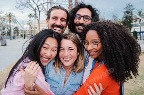 Preview: Group of joyful young adult friends hugging each others. Happy smiling multiracial people having fun
