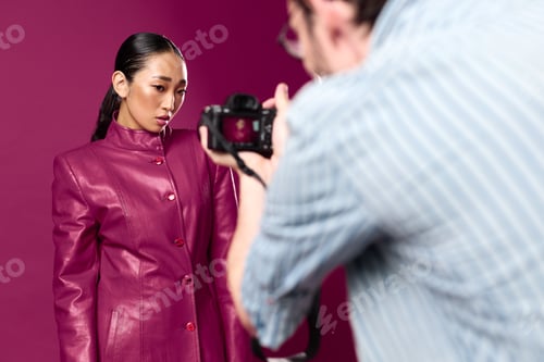 Preview: Fashionable asian brunette woman in a purple leather jacket posing in front of a matching purple