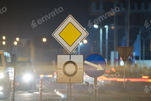 Preview: Roundabout road signs with blurred cars on city street traffic at night. Urban transportation