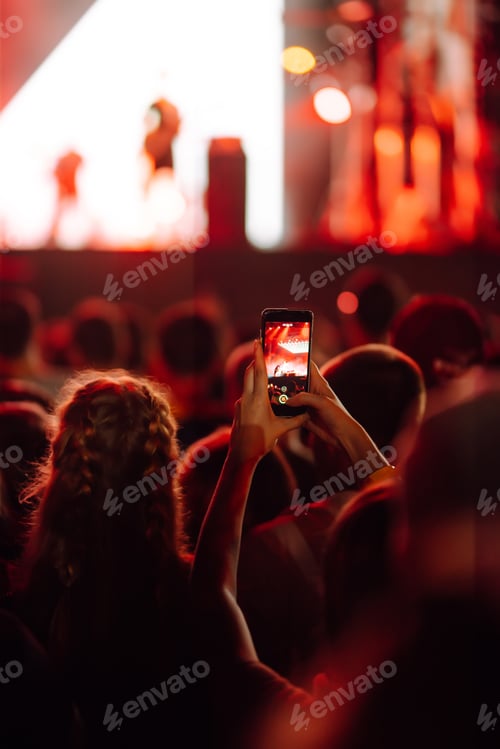 Preview: Fans enjoying rock concert with light show and clapping hands.