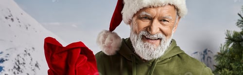 Preview: handsome Santa in Christmassy hat with red present bag smiling at camera, winter concept, banner