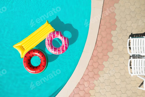 Preview: Inflatable rings and mattress floating in swimming pool, top view. Summer vacation