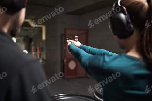 Preview: Young Woman Practicing Shooting Handgun at Indoor Firing Range