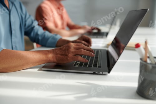Professionals Typing on Laptops at a White Desk