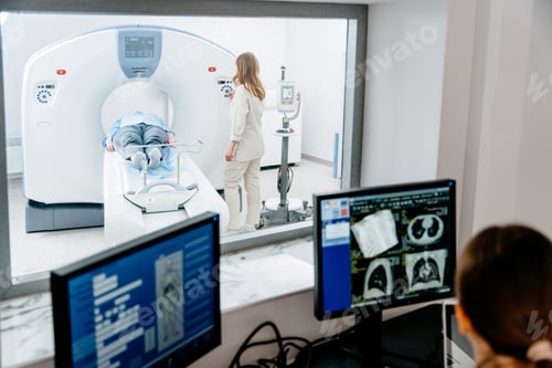 Preview: Female technician monitoring CT scan for male patient in hospital