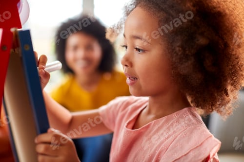 Preview: Mother And Daughter Having Fun Drawing Picture On Whiteboard At Home Together