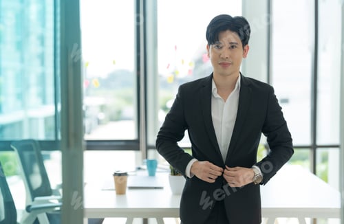 Preview: Smiling asian businessman standing in home office