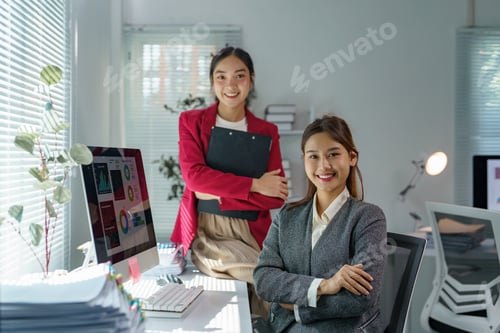 Preview: Two asian businesswomen are smiling and posing confidently in a modern office, showcasing teamwork,