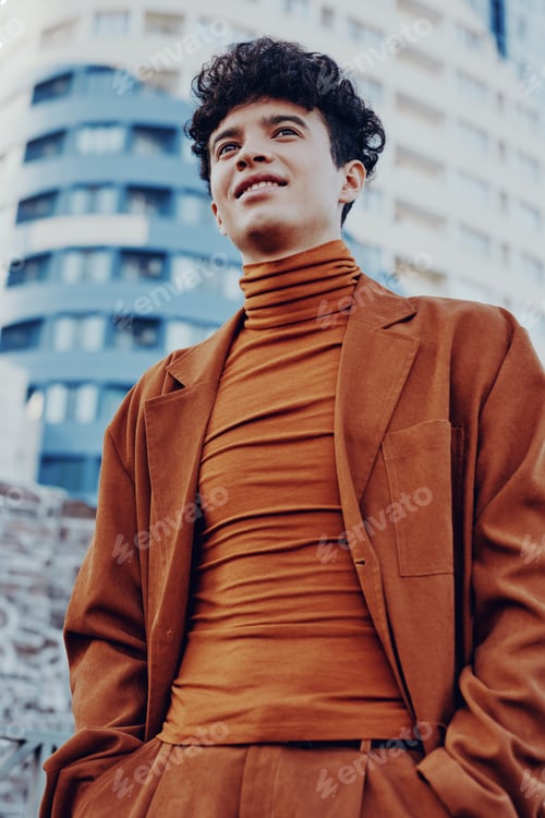 Preview: Young man in stylish brown outfit posing confidently in urban setting with modern buildings in the