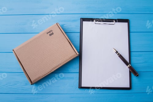 Preview: Clipboard and carton cardboard box, flat lay.