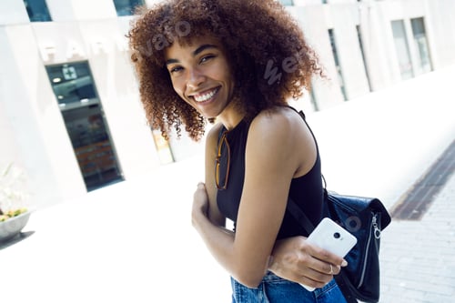 Preview: Beautiful young woman looking at camera in the street.