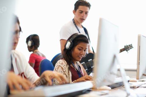 Visualização: Estudante universitária usando fones de ouvido tocando teclado olhando para baixo sorrindo