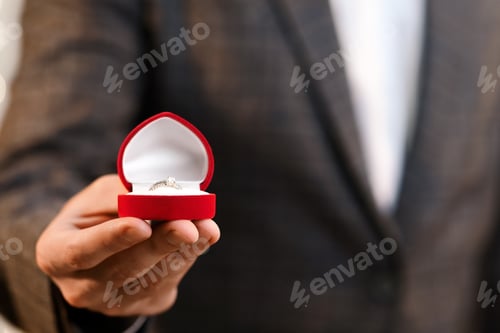 Preview: Unrecognizable man holding box with diamond ring and roses bouquet